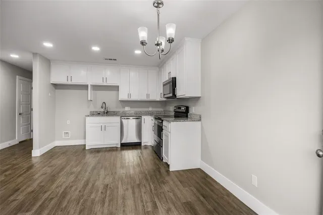 a kitchen with wooden floors and white cabinets