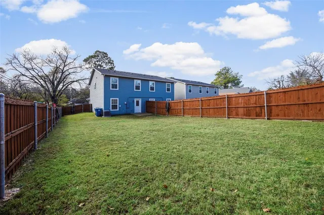 a view of a yard in front of a brick house with a large tree