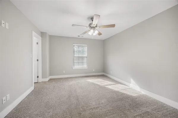 an empty room with chandelier fan and windows