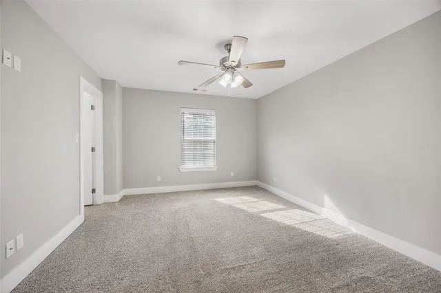 an empty room with chandelier fan and windows