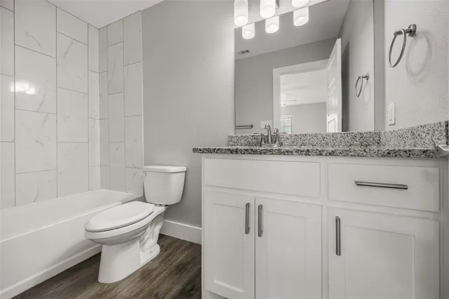 a bathroom with a granite countertop toilet sink and mirror