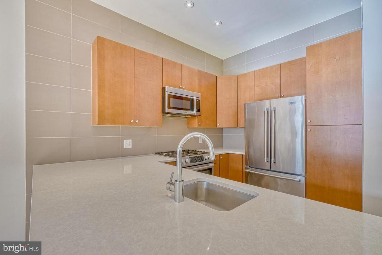 1209 North Charles Street, Unit 309 Baltimore, MD 21201 - Photo 7 of 11 a kitchen with refrigerator a microwave a sink and cabinets