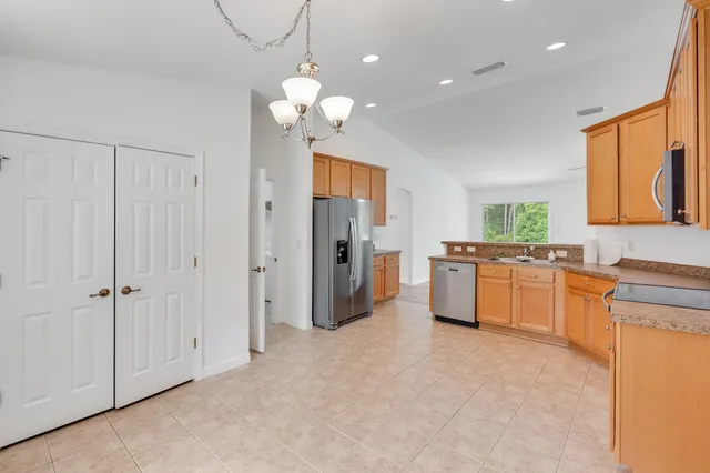 a large white kitchen with a refrigerator a sink dishwasher a stove and a dining table with wooden floor