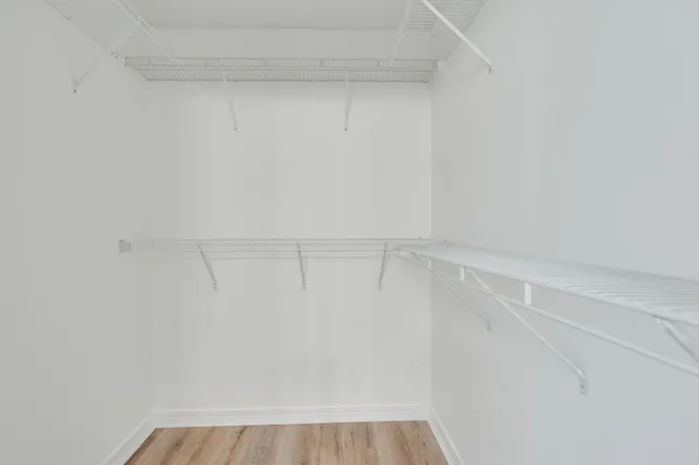 an empty room with wooden floor chandelier fan and windows