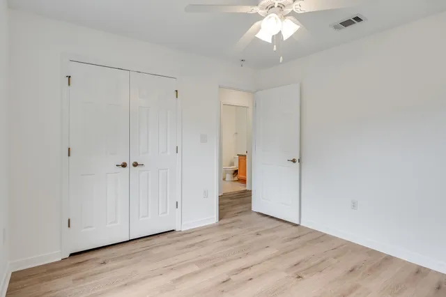 an empty room with wooden floor and ceiling fan