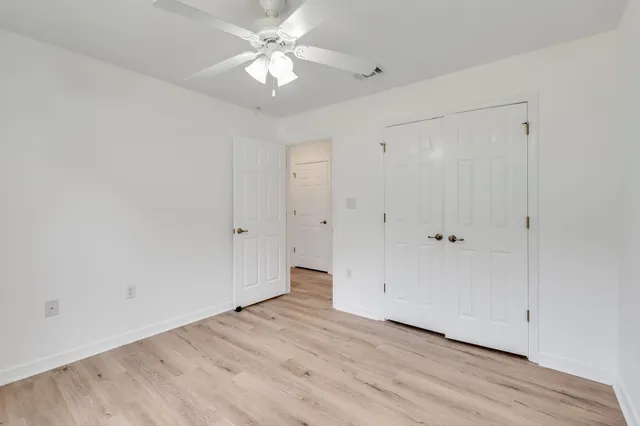 an empty room with a window and a chandelier fan