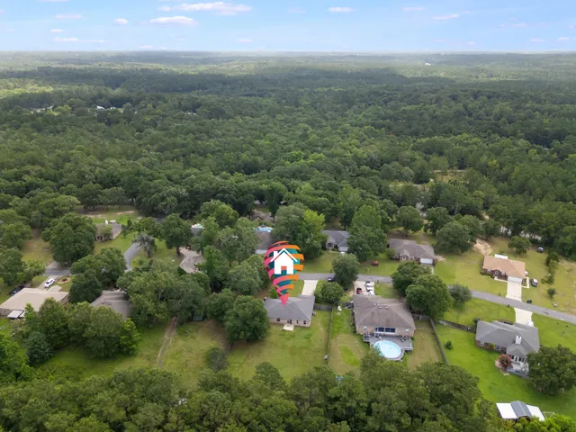 an aerial view of residential houses with outdoor space and trees