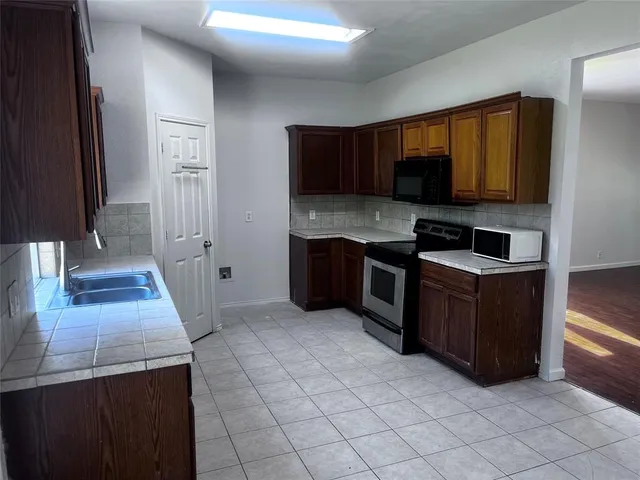 a kitchen with stainless steel appliances granite countertop a stove a sink and a microwave