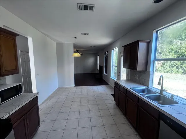 a large kitchen with granite countertop a sink and a stove top oven