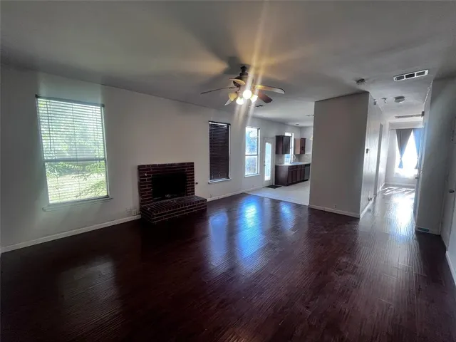 an empty room with wooden floor chandelier and windows