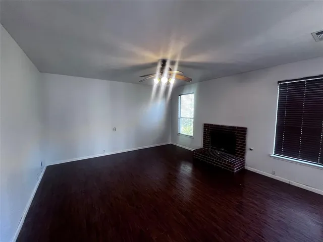 a view of wooden floor fire place and windows in an empty room