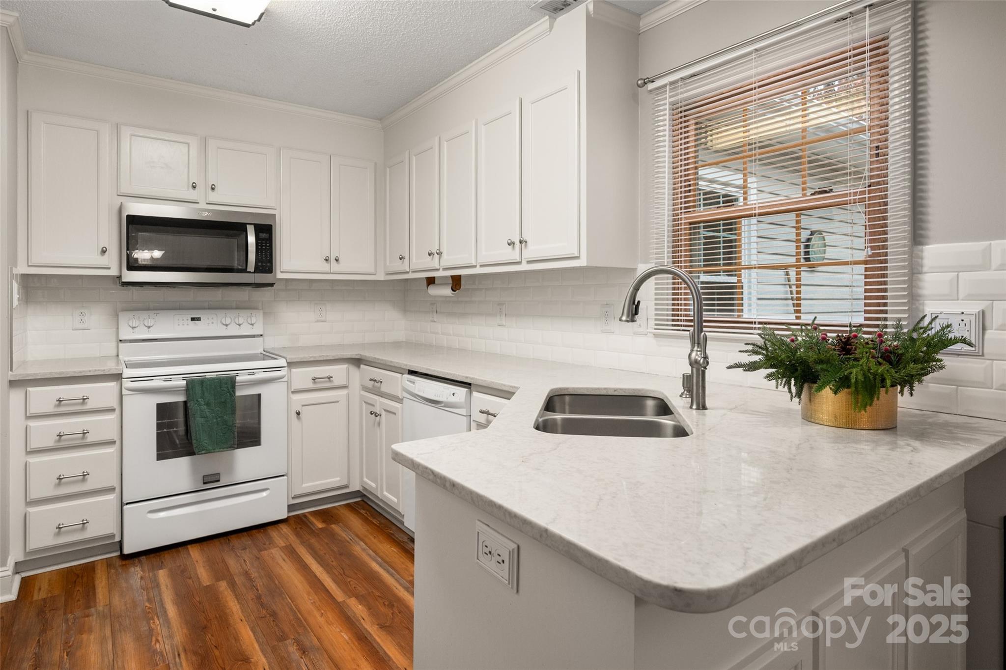 6045 Burnt Mill Run Matthews, NC 28104 - Photo 8 of 32 a kitchen with white cabinets a sink and a stove with wooden floor