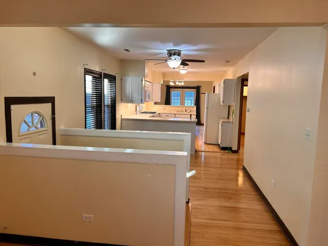 a view of a hallway with wooden floor and chandelier