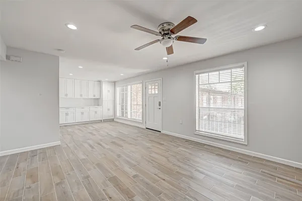a view of an empty room with wooden floor and a window