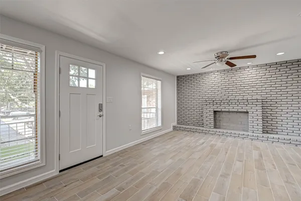 a view of an empty room with a window and wooden floor