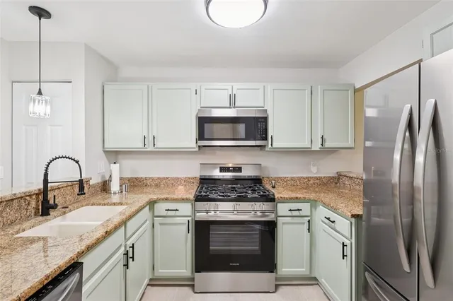 a kitchen with granite countertop a sink stove and refrigerator