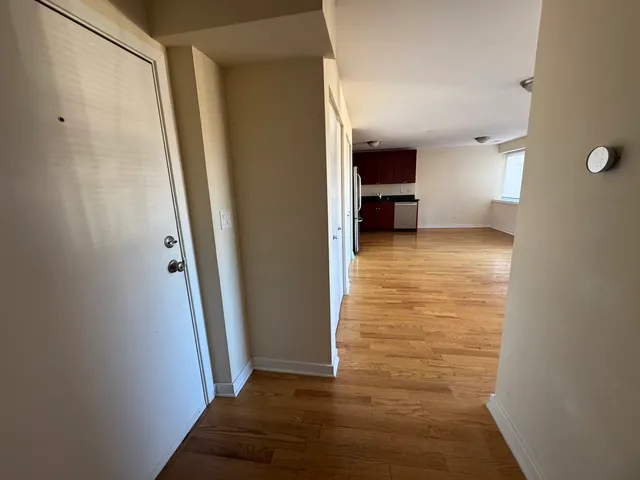 a view of a hallway with wooden floor and a bathroom