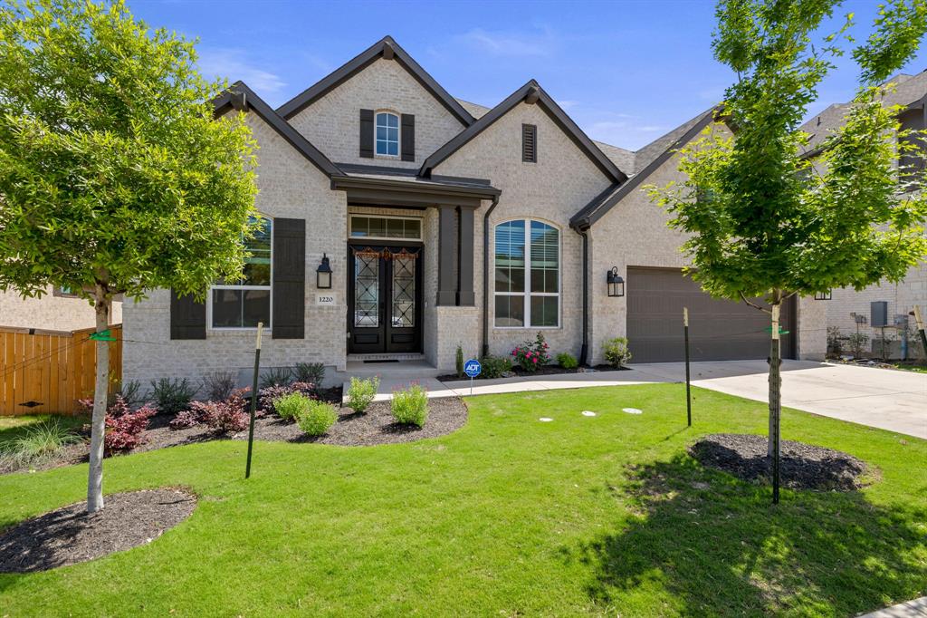 French country home with brick siding, driveway, french doors, and a garage