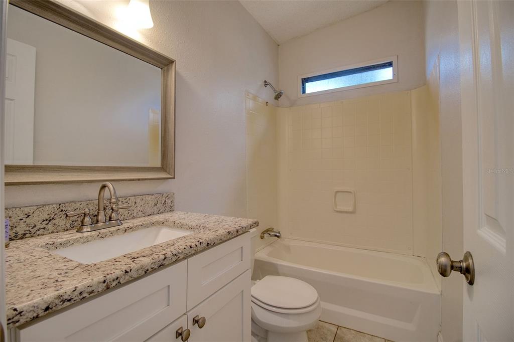 6804 Stafford Road Plant City, FL 33565 - Photo 13 of 24 a bathroom with a granite countertop sink a mirror and a toilet