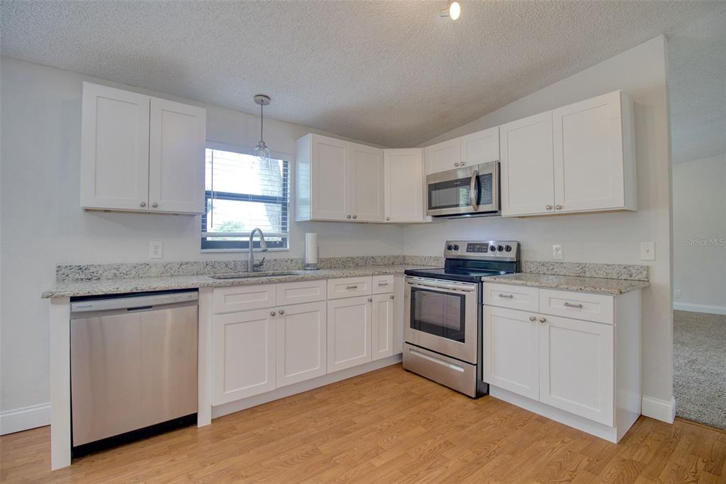 6804 Stafford Road Plant City, FL 33565 - Photo 7 of 24 a kitchen with granite countertop white cabinets sink and stainless steel appliances