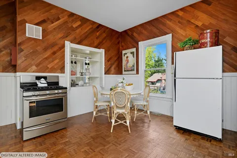 a kitchen with stainless steel appliances granite countertop a stove a refrigerator and a dining table with chair