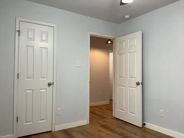 an empty room with wooden floor & closet area