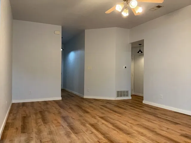 an empty room with wooden floor and fan