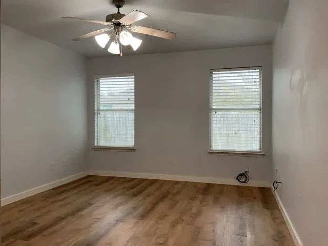 a view of an empty room with a window and wooden floor