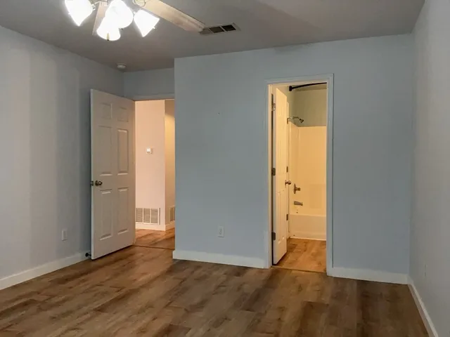 an empty room with wooden floor and a ceiling fan