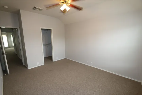 an empty room with a chandelier fan and windows