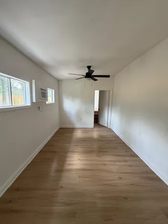 a view of empty room with wooden floor and fan
