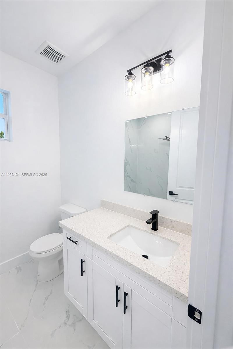 3901 East 19th Street Lehigh Acres, FL 33972 - Photo 7 of 11 a bathroom with a sink a toilet and mirror
