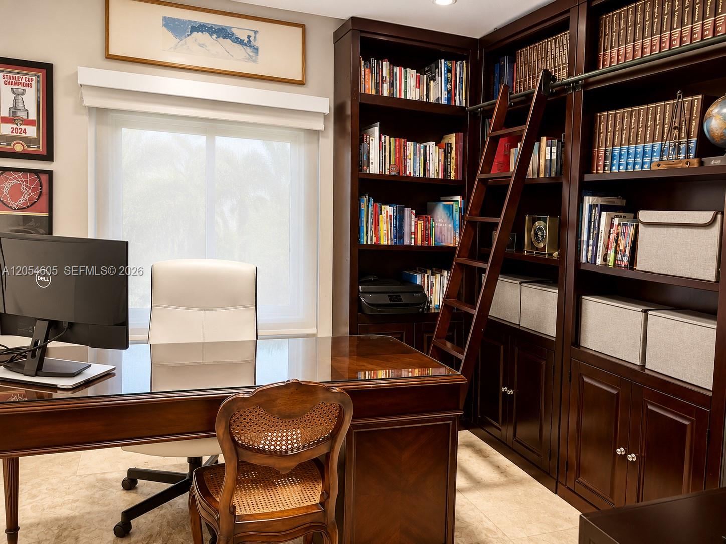 3538 Southwest 1st Avenue, Unit 1 Miami, FL 33145 - Photo 7 of 20 Private executive office designed for productivity and comfort. Features custom floor-to-ceiling built-in wood bookshelves with a rolling library ladder, extensive storage, and a spacious executive desk. Abundant natural light and marble floors create a bright, sophisticated workspace, ideal for working from home, studying, or managing a business in a quiet and elegant setting.