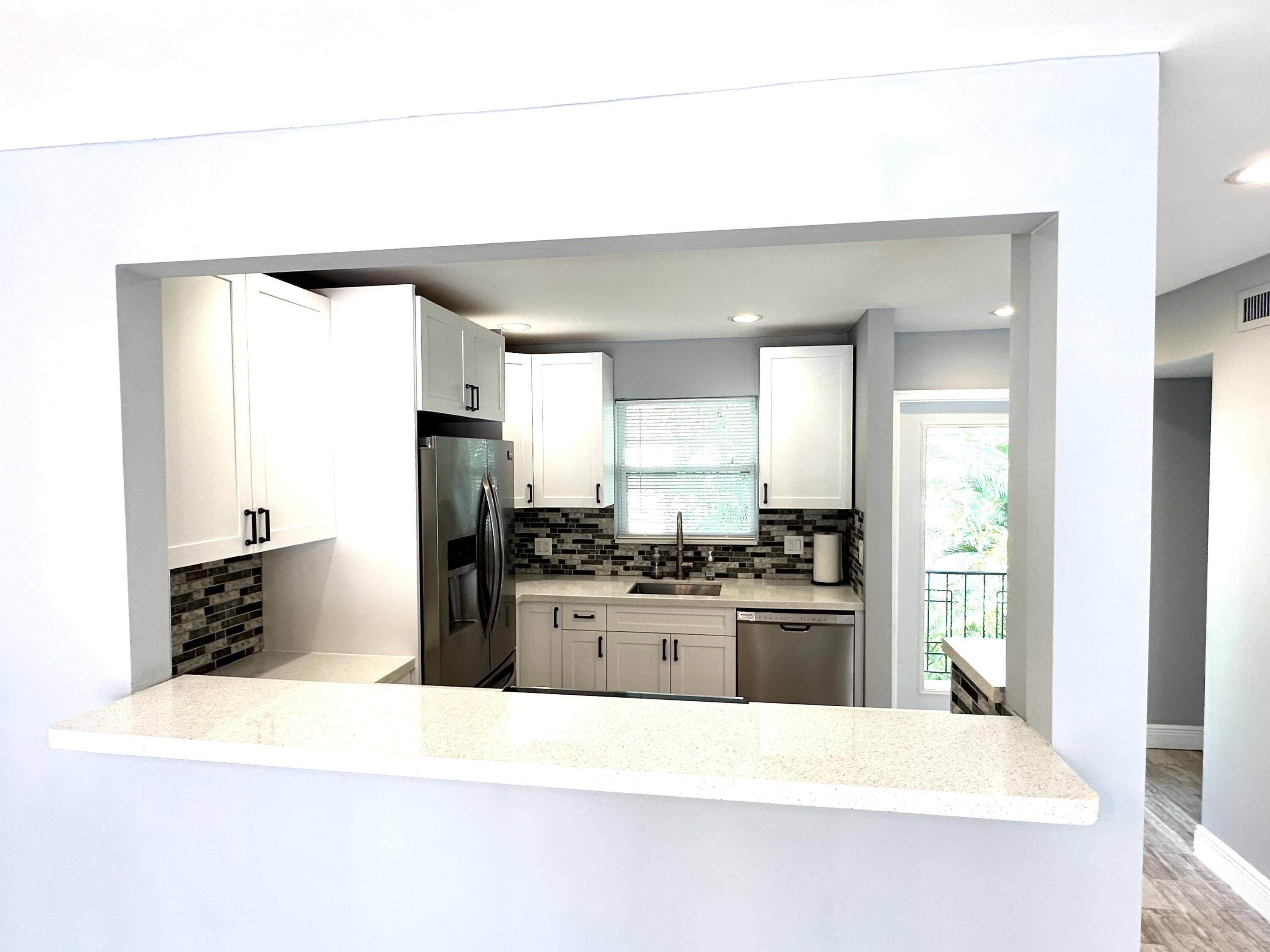 2162 Northeast 36th Street, Unit 46 Lighthouse Point, FL 33064 - Photo 4 of 15 a kitchen with stainless steel appliances kitchen island granite countertop a refrigerator a stove and a sink with large countertops