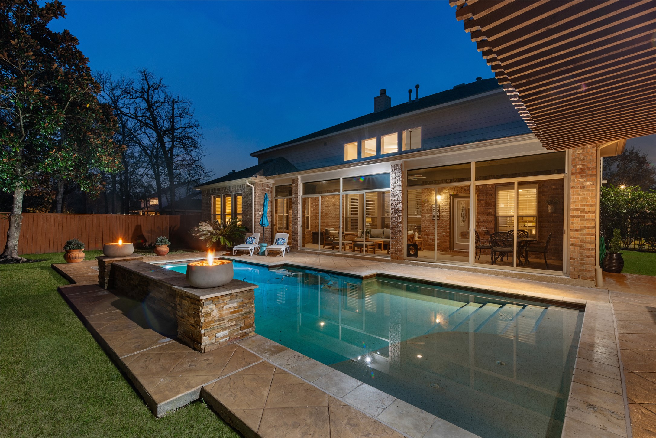 155 South Arrow Canyon Circle Spring, TX 77389 - Photo 1 of 49 The inviting backyard features a beautifully lit pool with water features and fireside accents, a spacious patio with seating and dining areas, and lush landscaping, perfect for relaxing and entertaining.