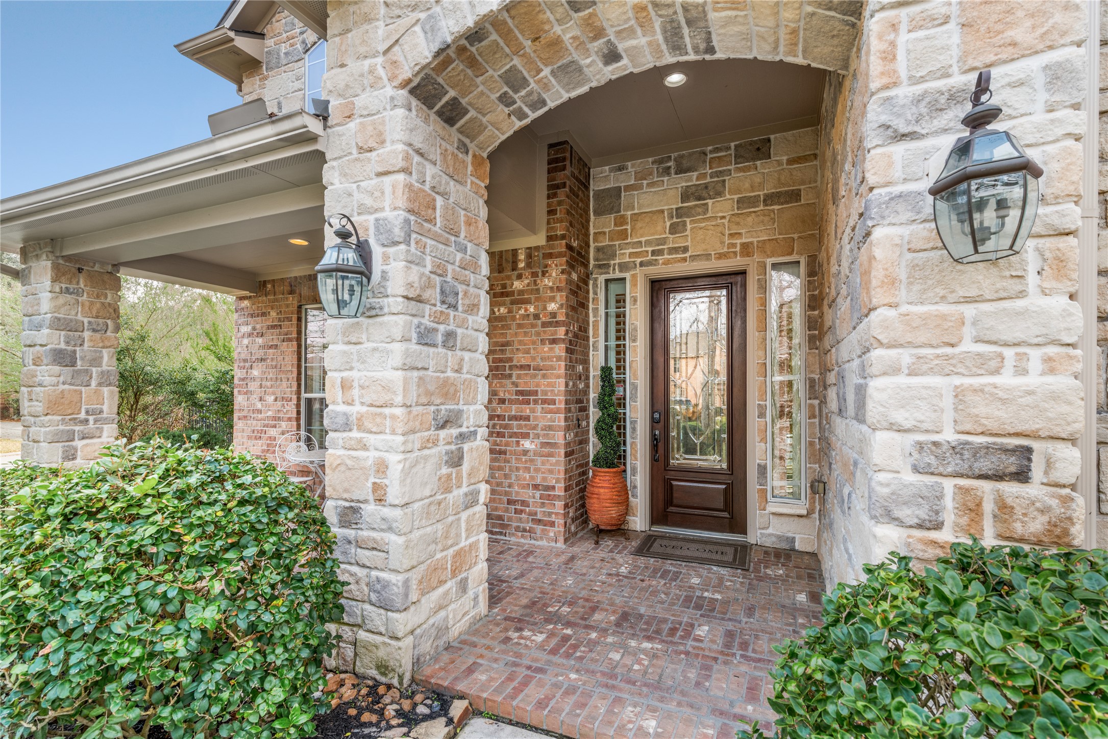 155 South Arrow Canyon Circle Spring, TX 77389 - Photo 4 of 49 The enticing entrance features a stone and brick facade and an arched doorway. The front door is flanked by tall windows. Elegant lantern-style lighting adds charm to the covered porch.