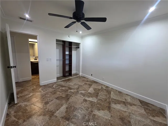 an empty room with closet and ceiling fan