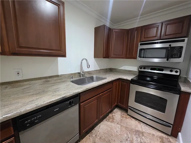 a kitchen with stainless steel appliances granite countertop a refrigerator a stove and a sink with wooden cabinets