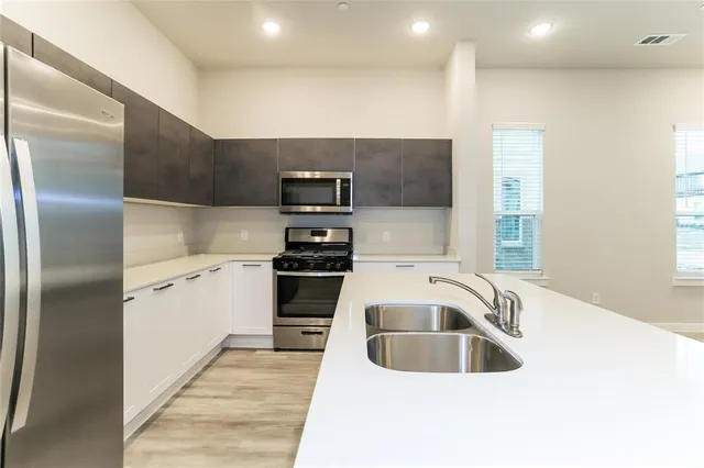 a kitchen with stainless steel appliances granite countertop a sink and a refrigerator