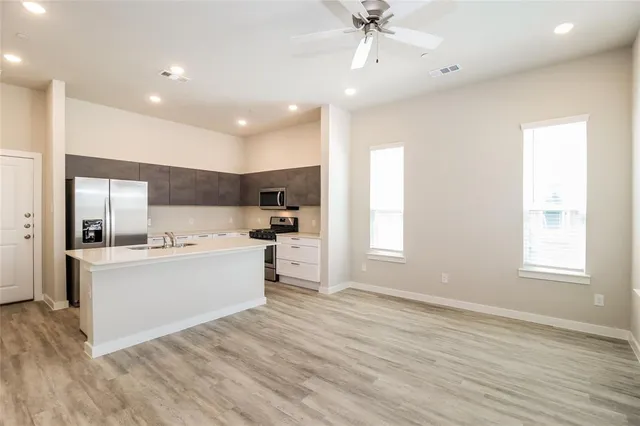 a view of a kitchen with kitchen island a sink wooden floor and a refrigerator