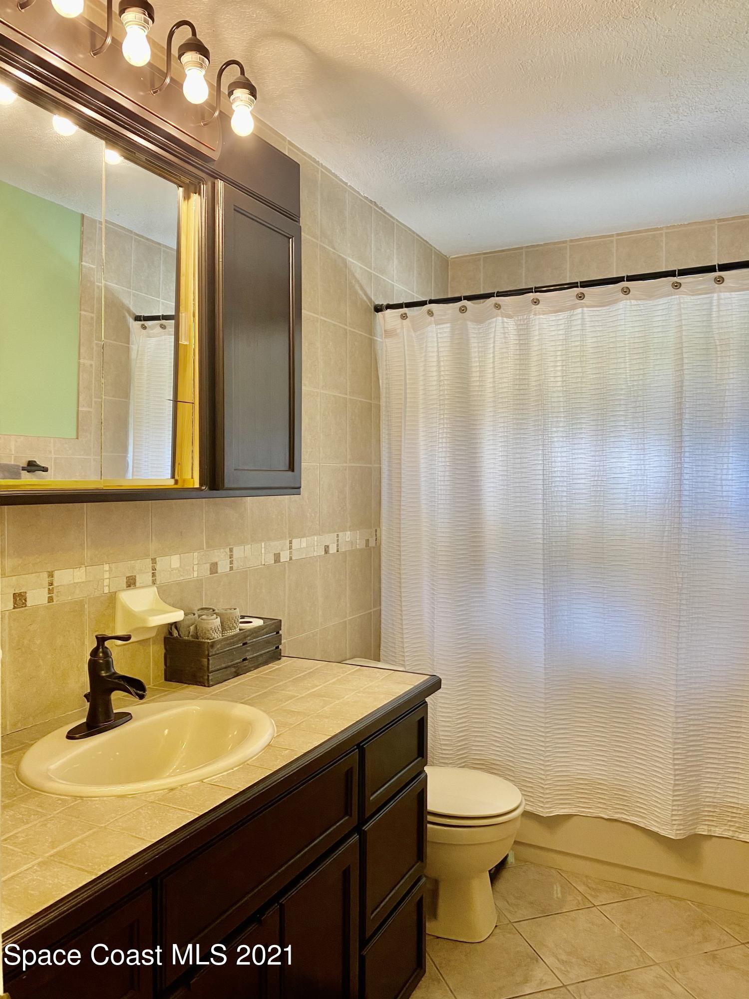 993 Cardon Drive Rockledge, FL 32955 - Photo 19 of 22 a bathroom with a sink a toilet and a mirror