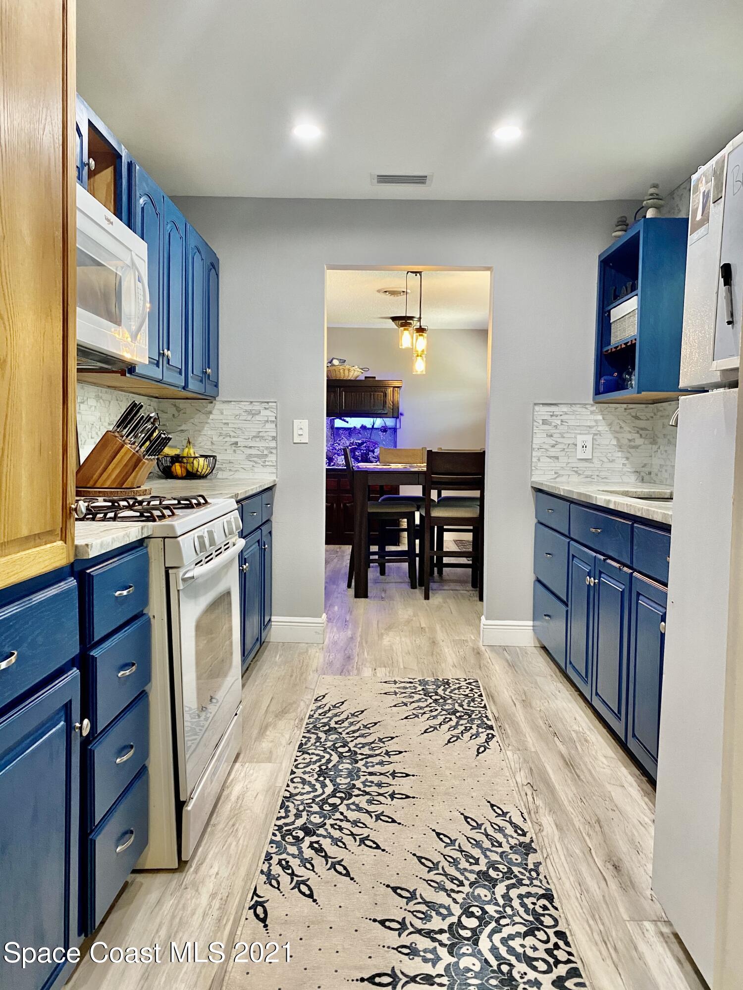 993 Cardon Drive Rockledge, FL 32955 - Photo 5 of 22 a kitchen with stainless steel appliances granite countertop a stove top oven a sink dishwasher and cabinets with wooden floor