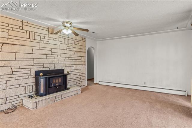 28018 County Farm Road Pueblo, CO 81006 - Photo 5 of 50 Unfurnished living room featuring baseboard heating, carpet, ceiling fan, and a fireplace