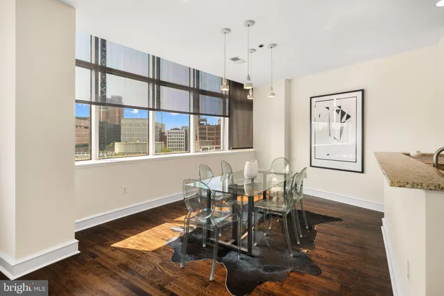 a dining room with wooden floor a chandelier a glass table and chairs
