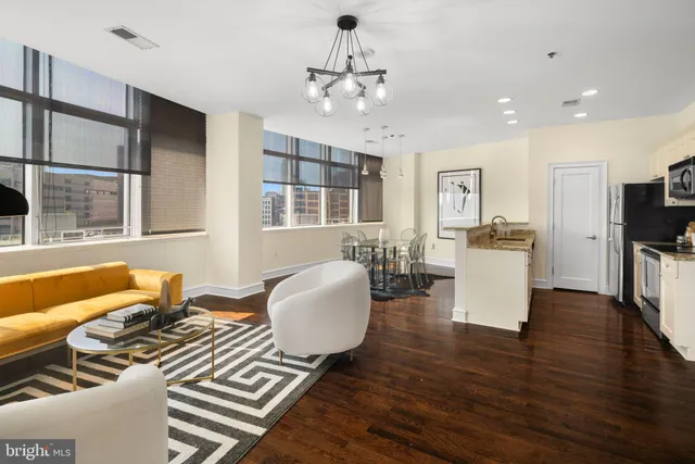 a living room with furniture two window and wooden floor