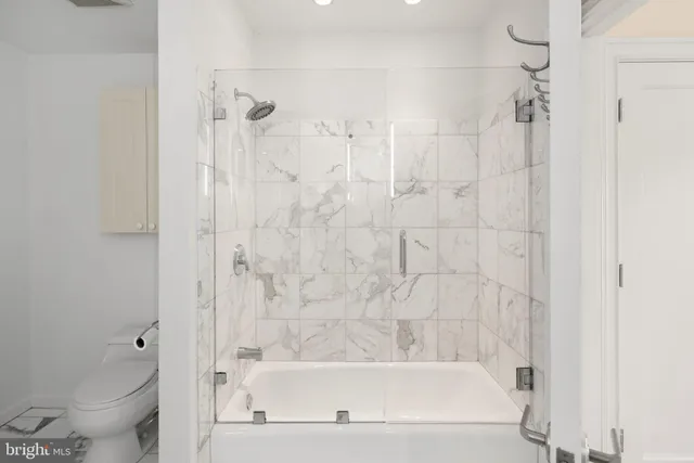 a bathroom with a bathtub shower and toilet