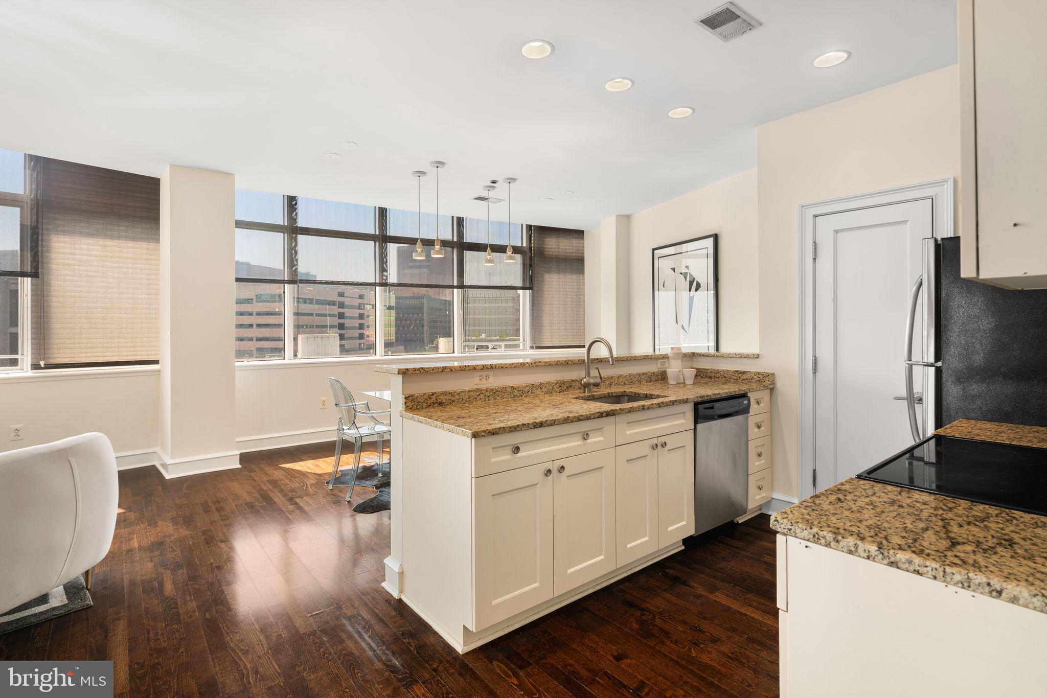 201-59 North 8th Street, Unit 603 Philadelphia, PA 19106 - Photo 7 of 35 a kitchen with granite countertop a sink cabinets stainless steel appliances and wooden floor