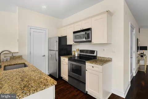 a kitchen with stainless steel appliances granite countertop a refrigerator stove top oven and sink