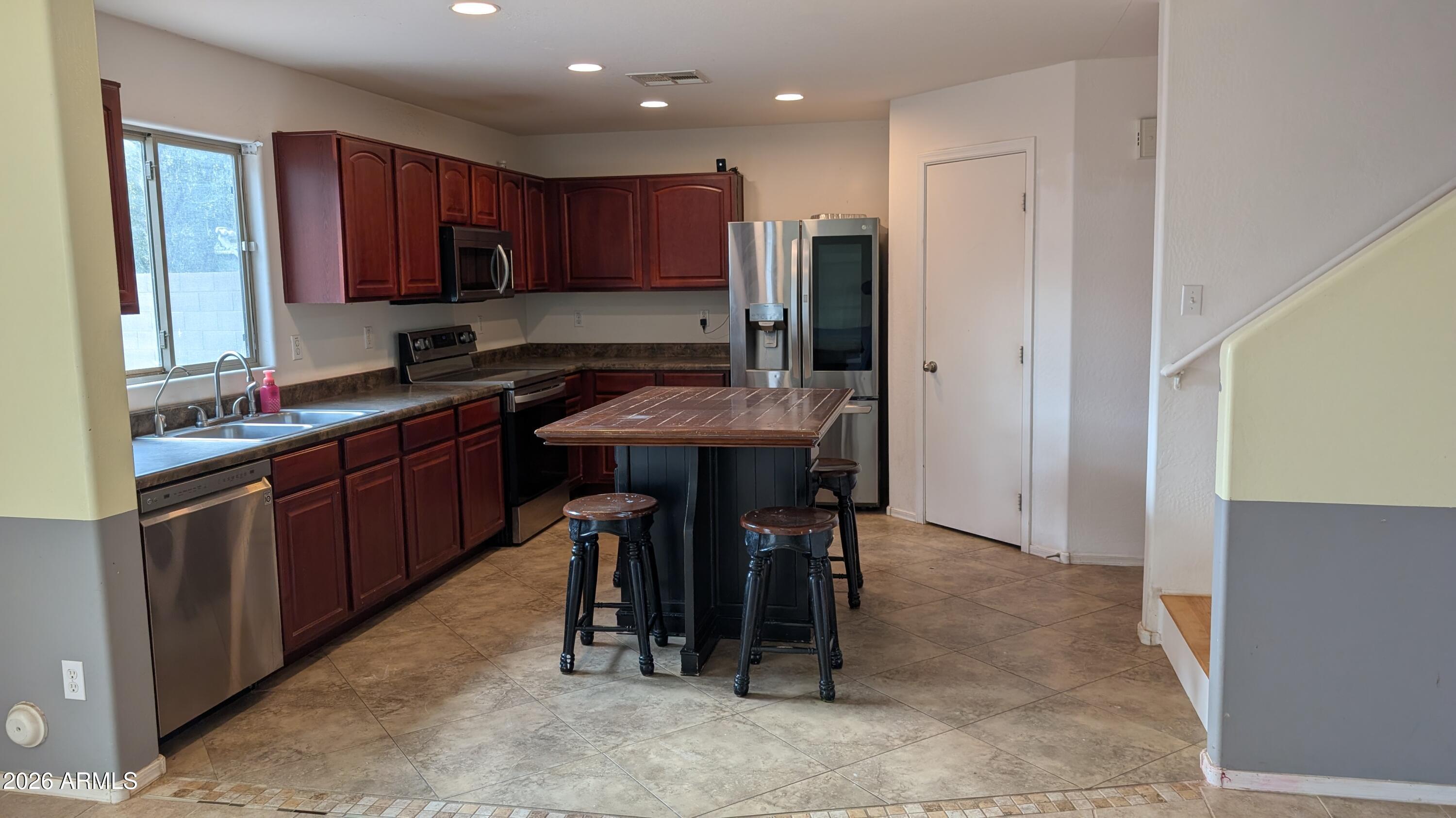 13229 East Primrose Lane Florence, AZ 85132 - Photo 8 of 11 a kitchen with stainless steel appliances granite countertop table chairs sink refrigerator and cabinets