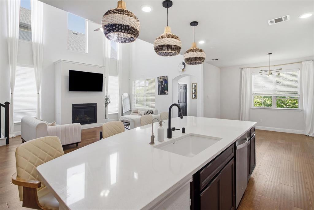 7416 Sequoia Rdg Road Little Elm, TX 76227 - Photo 23 of 37 Spacious kitchen island with a white countertop and integrated sink, complemented by three woven pendant lights